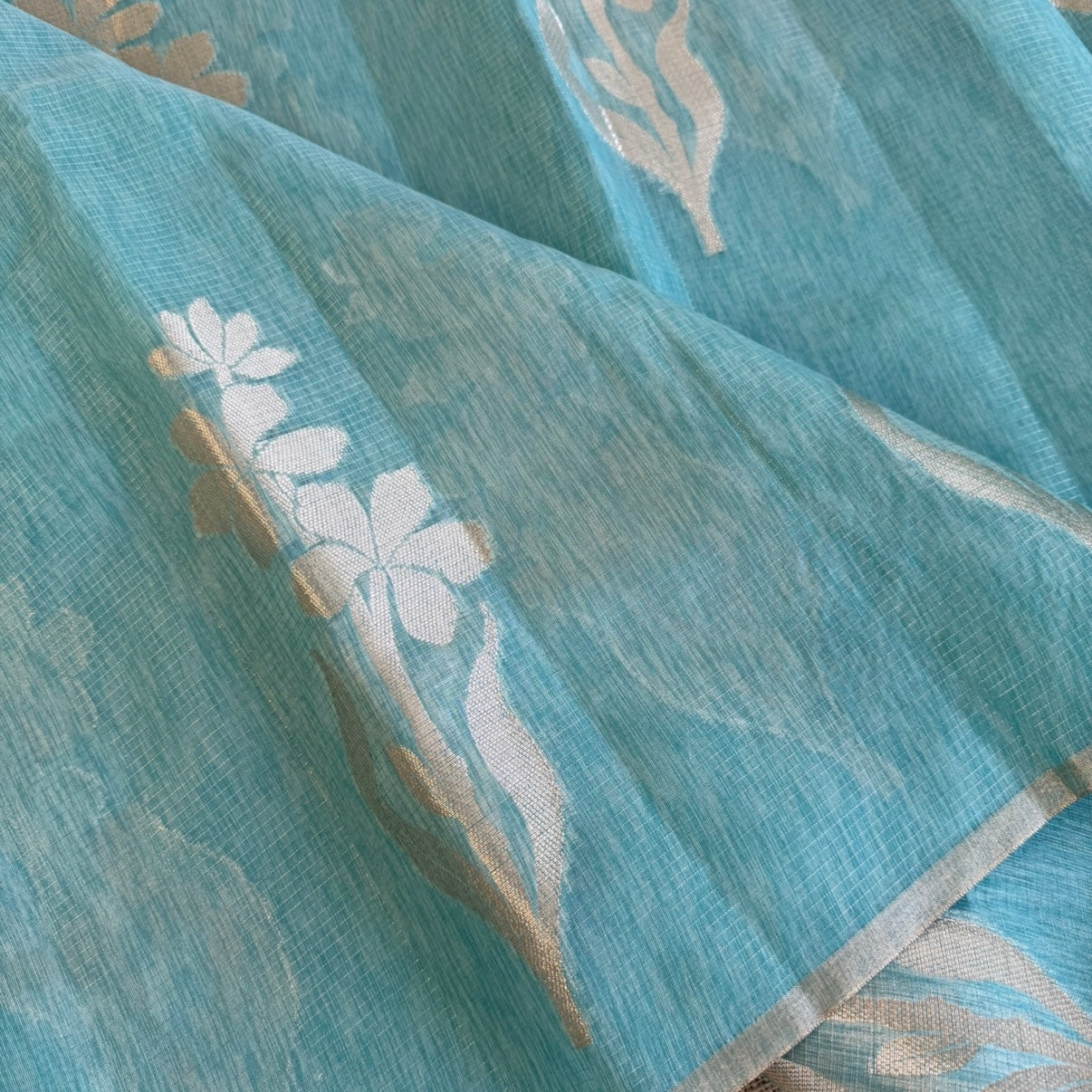 Sky blue paper silk saree with fine zari lines and floral zari weaving