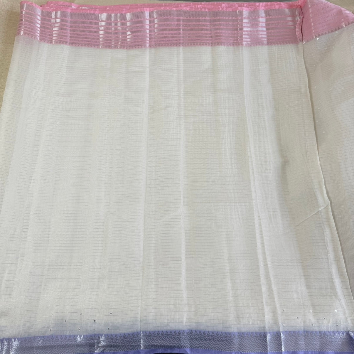 White fabric with pink and purple border on a plain background